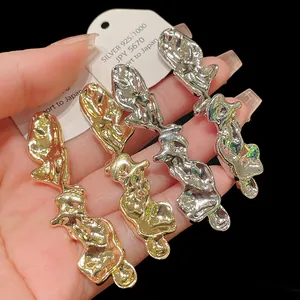 Dettaglio di orecchini irregolari in metallo liquido con finiture oro e argento