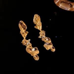 Primo piano dettagliato di orecchini d'oro fusi irregolari e lucidi per donne