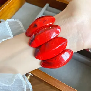 Dettaglio macro di un bracciale in acrilico marmorizzato rosso con maglie ovali