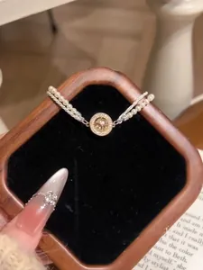 Détail macro d'un élégant bracelet double rang en perles et zircons dans son écrin en bois