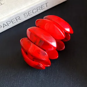 Dettaglio ravvicinato delle maglie ovali in acrilico marmorizzato rosso di un bracciale