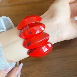 Primo piano di un braccialetto in acrilico marmorizzato rosso su un polso elegante