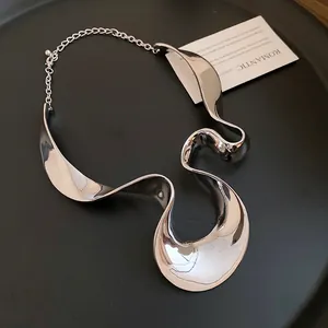 Gros plan d'un collier choker ruban ondulé en argent poli avec éclat métallique