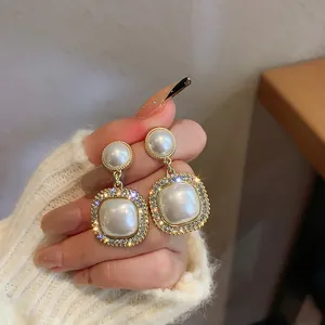 Primo piano di orecchini vintage in perle con bordo in strass tenuti in mano.