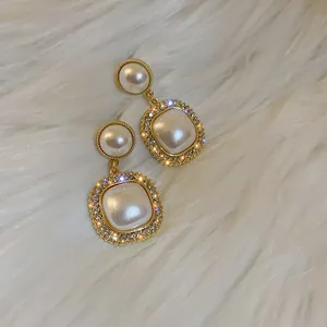 Dettaglio di orecchini vintage con perle francesi e bordi in strass su pelliccia bianca.