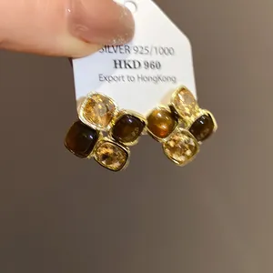 Dettaglio di orecchini a bottone retrò con pietre quadrate ambrate e marrone scuro