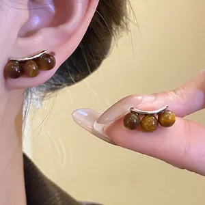 Dettaglio dei retro orecchini con perle marroni che mostra l'effetto indossato e la trama.