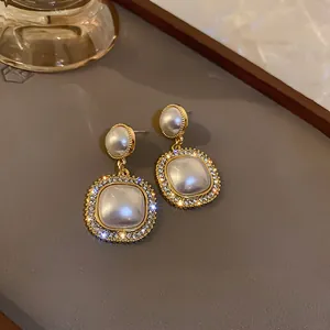 Dettaglio di orecchini di perle vintage francesi con bordi in strass su sfondo scuro.