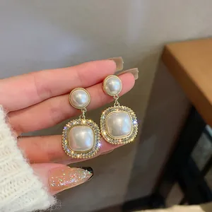 Dettaglio di eleganti orecchini pendenti con perle rétro e bordo di strass scintillanti