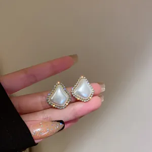 Dettaglio di eleganti orecchini a perno in perla vintage francese con bordo di strass