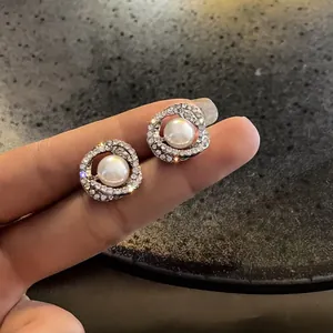 Dettaglio degli orecchini a perla vintage con accenti di strass scintillanti
