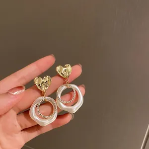 Vista dettagliata di orecchini vintage a cuore con perla bianca e anello di strass lucido