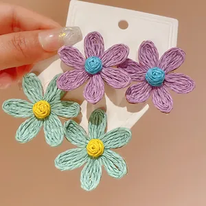 Detailed close-up of Bohemian woven flower stud earrings in mint green and purple