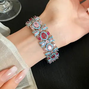 Close-up of ornate silver bracelet with pink and red oval crystals and turquoise accents.