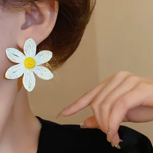 Detailed view of bohemian woven daisy earring with white petals and yellow center