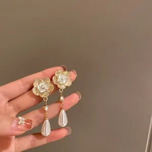 Dettaglio ravvicinato di orecchini a fiore di camelia vintage con eleganti perle a goccia