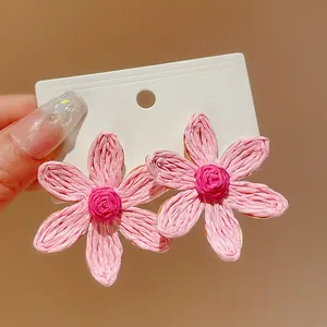 Detailed macro view of pink woven flower earrings with textured bohemian floral petals