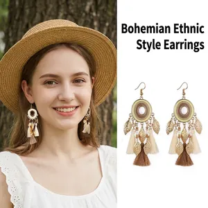 Detailed view of bohemian ethnic style earrings with metal leaves and cotton tassels.