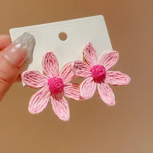 Detailed macro view of bohemian handmade pink woven flower stud earrings on card