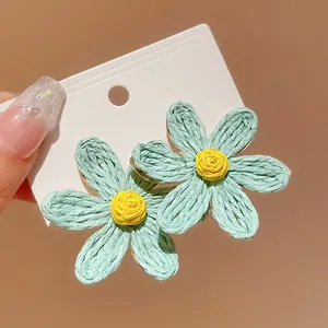 Close-up detail of bohemian style light blue woven flower earrings on a white card