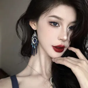 Detailed close-up of Bohemian vintage oil-drop earrings with blue cotton tassels on model