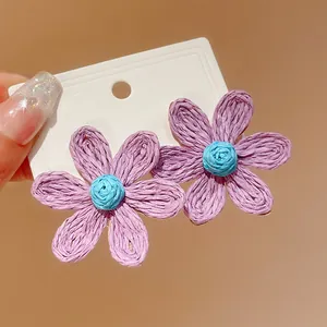 Close-up detail of bohemian hand-woven flower stud earrings featuring purple petals and blue center