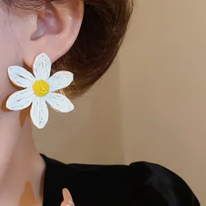 Macro close-up view of a bohemian white woven daisy earring on an Asian model's ear