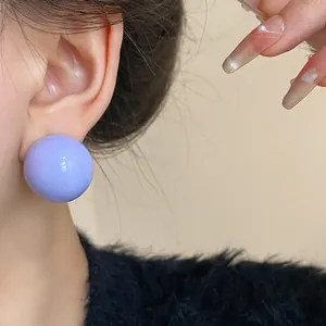Dettaglio ravvicinato di un orecchino a sfera lavanda lucido indossato elegantemente sull'orecchio
