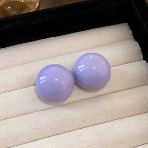 Primo piano dettagliato di orecchini a lobo a sfera viola su vassoio per gioielli.