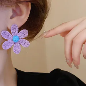 Detailed macro view of a bohemian purple woven flower earring with a blue center detail
