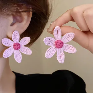 Macro detail of pink hand-woven flower earrings with delicate Bohemian style texture