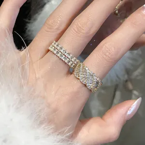 Primo piano di un anello di zirconi dorati intrecciati e fascia di perle al dito, fondo morbido