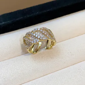 Dettaglio ravvicinato di un anello a fascia intrecciata placcato oro con zirconi.