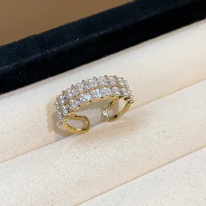Dettaglio di un elegante anello aperto con perle e zirconi in finitura dorata shiny