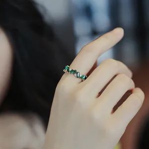 Detailed view showing a vintage gold-plated ring with green baguette zircons on a hand model.