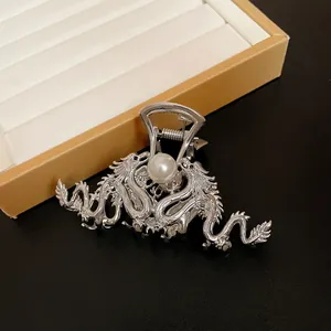 Close-up detail of a silver metal dragon hair claw clip with a central white pearl ornament
