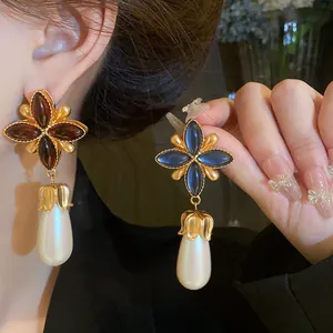 Orecchini vintage a fiore a quattro foglie con gemme scure e perle a goccia su modella