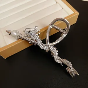 Close-up of silver dragon hair claw clip with rhinestones and pearl detail