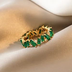 Detail view of an elegant gold-plated ring with emerald-green baguette stones and CZ