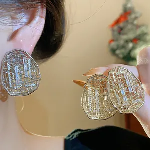 Close-up showing the intricate mesh design of gold-plated oval earrings with sparkling zircon