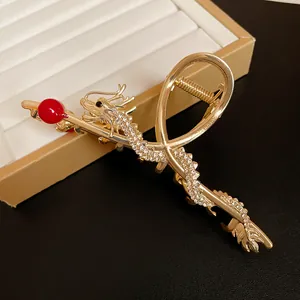 Detailed view of gold dragon hair claw clip with rhinestones and red bead