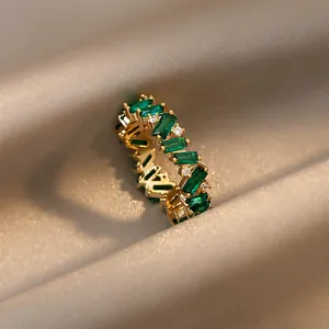 Macro view of an elegant gold plated ring featuring emerald green baguette zirconia gems.