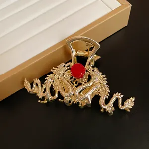 Close-up of a gold metal dragon-shaped hair claw clip with a central red bead ornament.