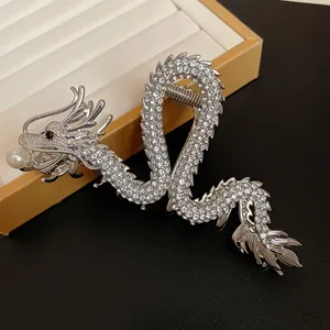Detailed view of a silver dragon hair claw clip paved with sparkling rhinestones and a pearl.