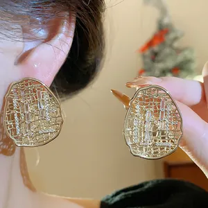 Close-up of gold-plated irregular oval stud earrings with hollow design and zircons