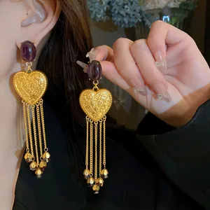 Primo piano di orecchini vintage a cuore color oro con gemme preziose viola