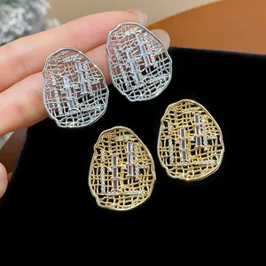 Detailed view of gold and silver plated oval hollow earrings with baguette zircons.