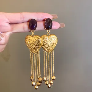 Dettaglio di orecchini a cuore vintage in oro con ametista e lunghe nappe