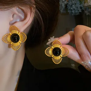 Primo piano di orecchini a fiore dorati in stile vintage francese con una gemma nera