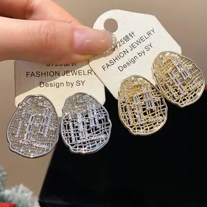 Close-up of gold and silver plated hollow oval stud earrings with zircon inlay